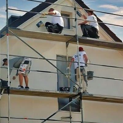 Mehrere Bauarbeiter auf Gerüst bei Fassadenarbeiten an Einfamilienhaus